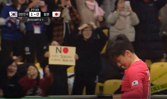 일본 제품 불매운동을 독려하는 ‘NO재팬’ 카드를 든 한국 응원객./축구 경기 중계 화면 캡처