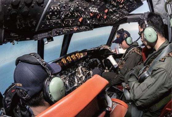 P-3C 조종실에서 정조종사와 부조종사, 기관조작사가 작전에 관한 의견을 나누고 있다. 유리창 너머로 동해가 보인다.