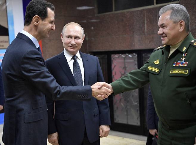 블라디미르 푸틴 러시아 대통령(가운데)이 7일 시리아 다마스쿠스를 방문했다. 동행한 세르게이 쇼이구 러시아 국방장관이 바샤르 알아사드 시리아 대통령(왼쪽)과 악수를 나누는 모습을 푸틴 대통령이 지켜보고 있다.  크렘린·AP연합뉴스