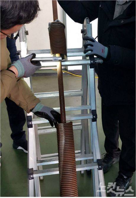 셔터 추락 사고 현장 검증에 나선 국과수 관계자들이 파손된 스프링을 살펴보고 있다. (사진=부산CBS 박진홍 기자)