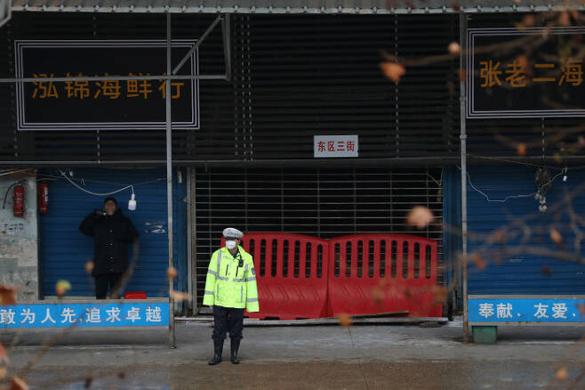 지난 10일 중국 후베이성 성도 우한에서 경찰이 마스크를 쓴 채 폐쇄된 수산시장 앞에서 보초를 서고 있다. 이 수산시장이 신종 코로나바이러스에 의한 폐렴 발병의 진원지로 지목돼 폐쇄된 가운데 신종 폐렴 확진환자들 중 일부는 이 수산시장을 방문한 적이 없다고 말했다. 로이터연합