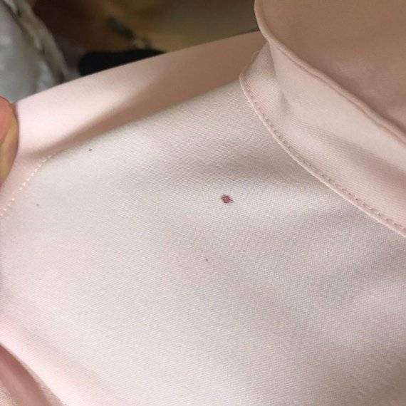 길병원 한 간호사가 피 묻은 근무복을 들어보이고 있다. 다수 간호사는 일상적인 업무과정에서 환자의 체액과 타액이 근무복에 묻을 수 있다고 증언한다. 전국보건의료산업노조 가천대길병원지부 제공.