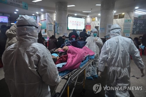 우한 적십자병원으로 이송되는 환자 (우한 AFP=연합뉴스) 방호복을 입은 의료진들이 25일 중국 우한 적십자병원으로 한 환자를 이송하고 있다. jsmoon@yna.co.kr
