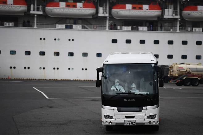 일본 가나가와현 요코하마항에서 버스 한대가 코로나19 집단 감염이 발생한 크루즈선 ‘다이아몬드 프린세스’ 앞에 서 있다. 이 배에서 일부 고령자들이 이날 오후부터 조기 하선해서 사이타마현 정부 시설로 이동했다. 요코하마/AFP 연합뉴스