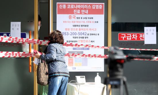 확진자가 다녀가 폐쇄된 대구시 중구 경북대학교 병원 응급실에서 19일 한 환자가족이 환자에게 전해줄 물품을 응급실 관계자에게 맡기고 있다. 연합뉴스