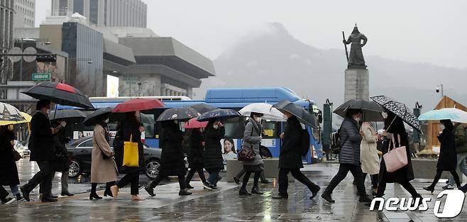 봄을 재촉하는 비가 내리는 25일 오전 서울 종로구 광화문 네거리에서 마스크와 우산을 쓴 시민들이 출근하고 있다. 2020.2.25/뉴스1 © News1 안은나 기자
