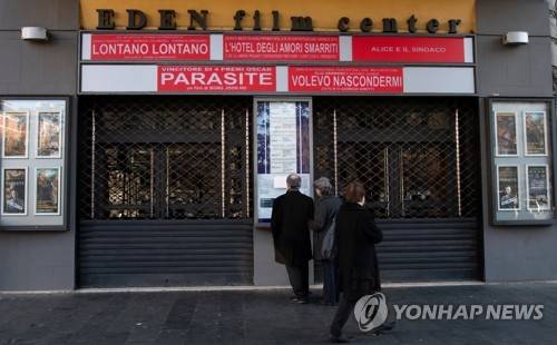'휴관 안내문' 게시된 로마의 영화관 (로마 AFP=연합뉴스) 이탈리아에서 신종 코로나바이러스 감염증(코로나19) 확산을 막기 위해 오락 시설에도 일제히 폐쇄령이 내려진 8일(현지시간) 로마 시내의 한 영화관 앞에서 시민들이 휴관을 알리는 안내문을 읽고 있다. leekm@yna.co.kr