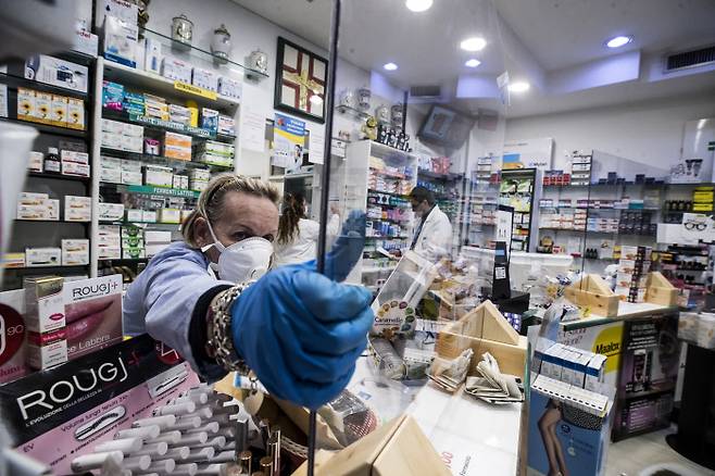 14일(현지시간) 이탈리아 로마의 한 약국 직원이 코로나19 감염을 막기 위해 고객 상담창구에 투명 아크릴판을 세우고 있다.  로마 | EPA연합뉴스