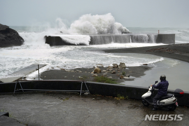 [구마노=AP/뉴시스] 지난해 10월12일 일본 미에현 구마노 해변에 제19호 태풍 하기비스의 영향으로 거센 파도가 방파제를 덮치는 모습을 한 남성이 스쿠터에 앉아 바라보고 있다.  2019.10.12.
