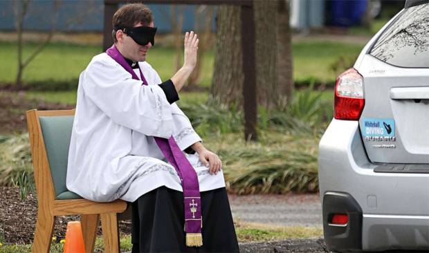 코로나19 사태로 교회 등 다중이용시설 출입이 제한된 가운데, 미국 메릴랜드주 보위 지역 한 성당의 스콧 홀머 신부가 주차장에 ‘야외 고해실’을 마련하고 ‘드라이브 스루 고해성사’를 받고 있다.