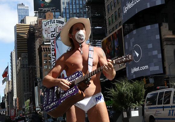 미국에서도 뉴욕주에서 가장 코로나19로 인한 피해가 집중되는 가운데 2일(현지시간) 뉴욕에서 가장 번화했던 타임스퀘어에서 거의 벌거벗은 채 마스크를 쓴 카우보이 남성이 텅 빈 거리를 배경으로 노래를 들려주고 있다.뉴욕 AFP 연합뉴스