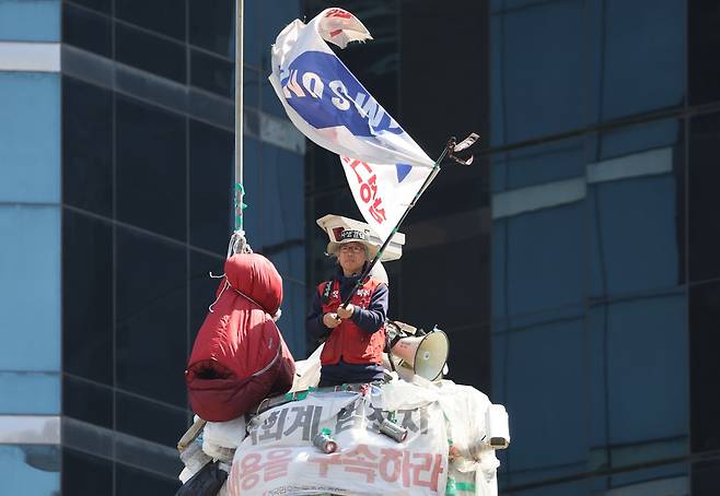 4일 오후 서울 강남구 강남역사거리에서 김용희씨가 고공농성 300일을 맞아 연대 집회를 하는 참가자들을 향해 깃발을 흔들고 있다. 이정아 기자