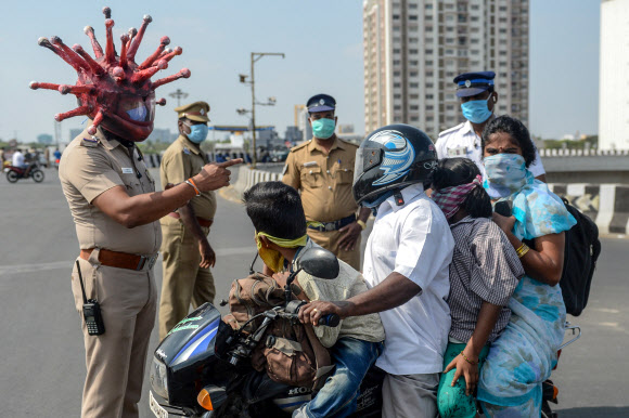 - 신종 코로나바이러스 감염증(코로나19) 확산에 대한 우려가 전세계적으로 커지고 있는 가운데 28일(현지시간) 인도 첸나이에서 코로나바이러스를 형상화한 헬멧을 쓴 경찰관이 시민들을 상대로 조사를 펼치고 있다.AFP 연합뉴스