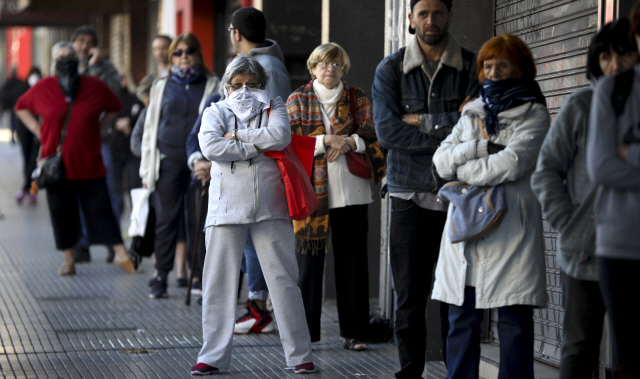 4일(현지시간) 아르헨티나 부에노스아이레스의 한 은행 앞에 연금을 인출하려는 사람들이 긴 줄을 이루며 차례를 기다리고 있다. 이날 은행은 연금을 수령하려는 사람들을 위해 주말에도 문을 열었다./부에노스아이레스=AP연합뉴스