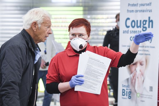 핀란드 헬싱키 국제공항 직원들이 마스크와 장갑을 착용한채 여행객들에게 코로나19 관련 주의사항을 애기하고 있다. [EPA= 연합뉴스]