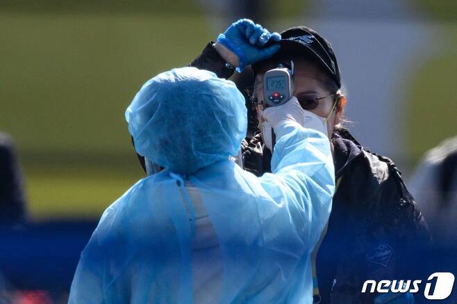 의료용 방호복 차림의 일본 방역당국 직원이 지난 2월21일 요코하마항에서 국제 크루즈선 '다이아몬드 프린세스' 승객을 상대로 발열검사를 하고 있다. © AFP=뉴스1
