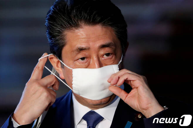 아베 신조 일본 총리가 지난 6일 관저에서 기자들의 질문에 답하기에 앞서 마스크를 벗고 있다. © 로이터=뉴스1