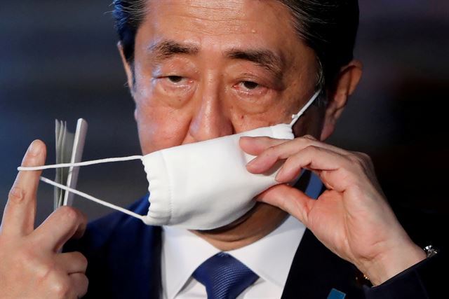아베 신조 일본 총리가 6일 도쿄 총리관저에서 기자들의 질문에 답변하기 위해 마스크를 벗고 있다. 도쿄=로이터 연합뉴스