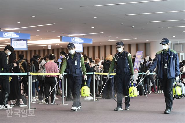 방역업체 관계자들이 17일 오후 인천국제공항 제2여객터미널 2층 입국장 검역대 앞에서 입국자들의 발길이 닿는 바닥에 살균소독제를 뿌리고 있다. 영종도=이한호 기자
