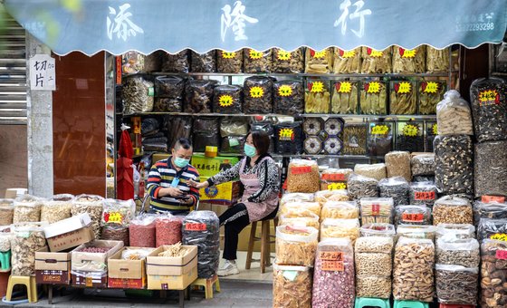 지난달 17일 중국 광둥성 광저우의 한 한약재상에 마스크를 낀 남여가 앉아 있다. 최근 중국에선 코로나19에 효험이 있다며 감기용 한약을 사재기하는 현상이 벌어지고 있다고 한다. [EPA=연합뉴스]