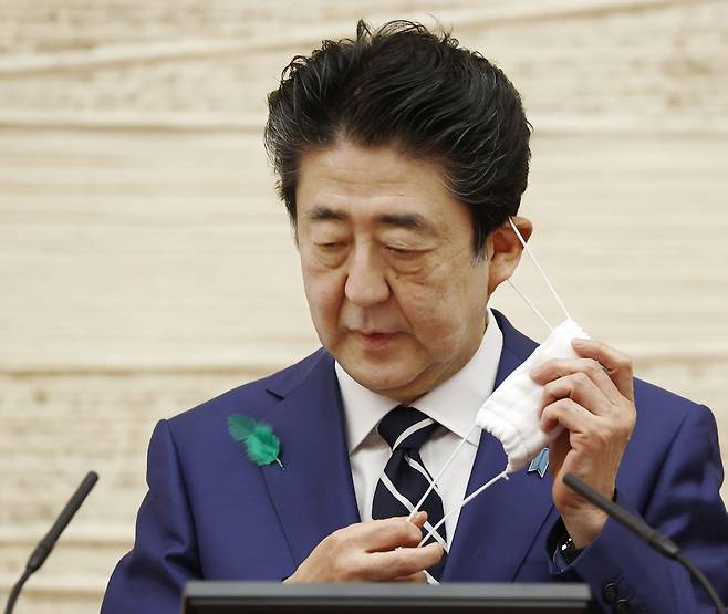 아베 신조(安倍晋三) 일본 총리가 지난달 총리관저에서 기자회견에 앞서 마스크를 벗고 있다. 2020.5.12