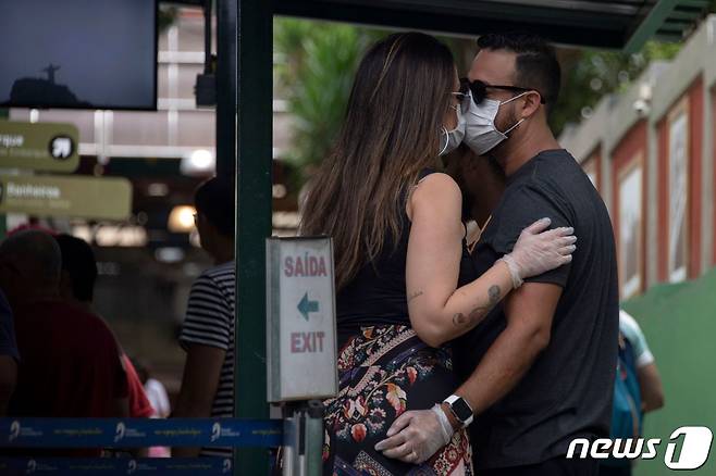 17일 (현지시간) 세계적인 코로나19 확산 속 브라질 리오데자네이로에서 마스크 쓴 여행 커플이 버스 티켓을 사기위해 기다리면서 키스를 하고 있다. © AFP=뉴스1 © News1 우동명 기자