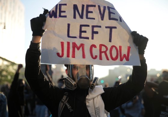 지난 5월 29일 미국 미네소타주 미니애폴리스에서 벌어진 시위에 참가한 시민이 '짐 크로 법을 놔두지 않겠다'는 구호를 적어 보이고 있다. 짐 크로 법은 흑백 분리와 차별을 정당화한 법들을 가리킨다. AFP=연합뉴스
