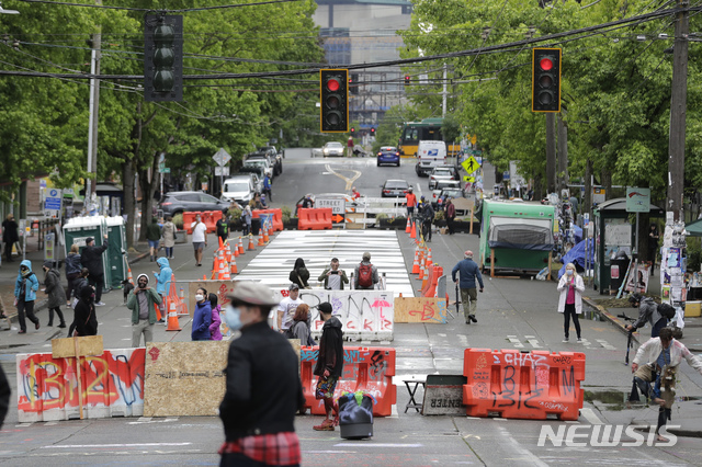 [시애틀=AP/뉴시스]11일(현지시간) 워싱턴 시애틀에서 행인들이 칼 앤더슨 공원 인근 도로에 설치된 바리케이드를 지나고 있다. 2020.06.12.