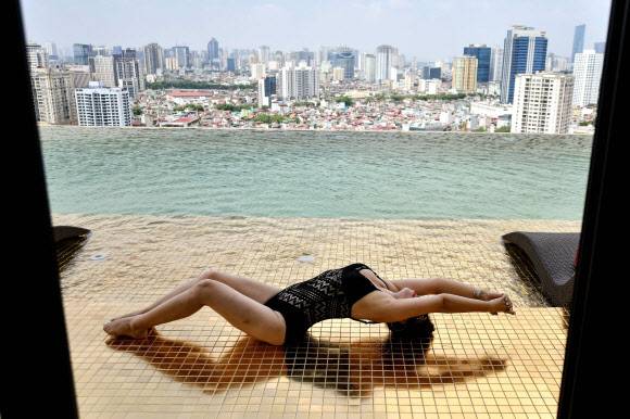 한 여성이 2일(현지시간) 베트남 하노이에 새로 문을 연 ‘돌체 하노이 골든 레이크 호텔’의 금으로 도금한 객실 루프탑 인피니티풀에서 기념촬영을 하고 있다.AFP 연합뉴스