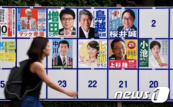 지난달 28일 일본 도쿄에서 한 여성이 도쿄도지사 선거 후보들의 포스터 앞을 지나고 있다. © AFP=뉴스1