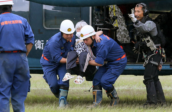 일본 자위대 소속 의사들이 5일(현지시간) 일본 구마모토현에 폭우가 내린 뒤, 재난지역에서 군용 헬기에 의해 대피한 한 노인을 이동시키고 있다. AFP 연합뉴스