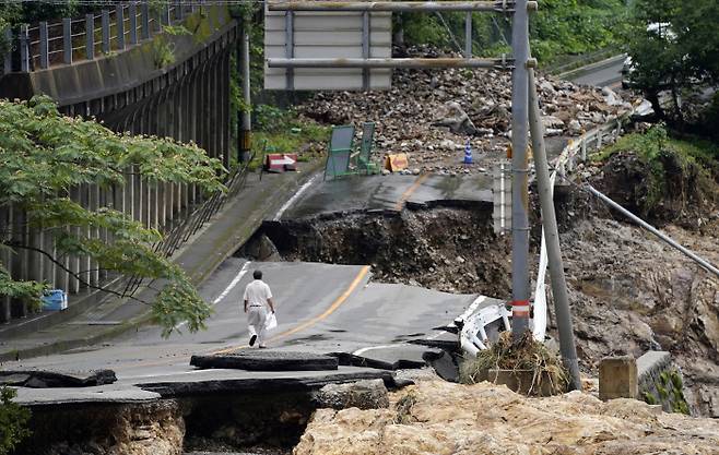 일본 서부 구마모토현의 구마무라에서 6일 한 주민이 폭우로 무너져 내린 도로를 걸어가고 있다.     구마무라｜교도연합뉴스