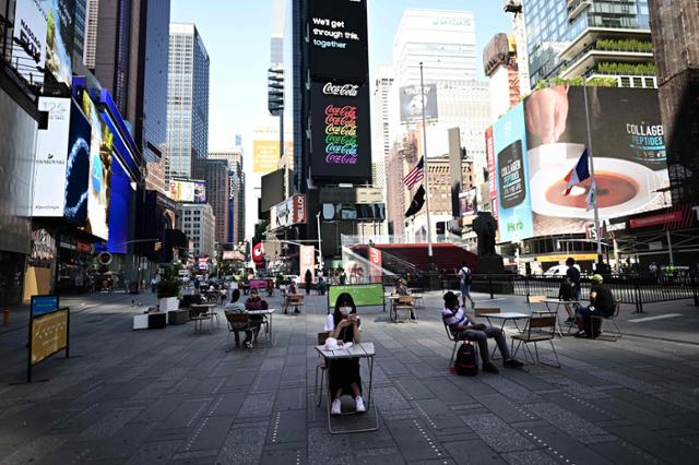 미국에서 신종 코로나바이러스 감염증(코로나19)으로 가장 큰 타격을 입었던 뉴욕시가 2단계 경제 재개 조치에 들어간 지난달 22일(현지시간) 맨해튼 중심가 타임스퀘어에서 사람들이 '사회적 거리두기'를 지키며 탁자에 앉아 있다. 뉴욕=AFP 연합뉴스