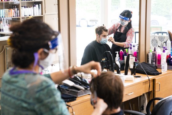 미국 워싱턴 DC의 한 미용실에서 미용사들이 마스크와 페이스실드를 착용하고 머리 손질을 하고 있다. [EPA=연합뉴스］
