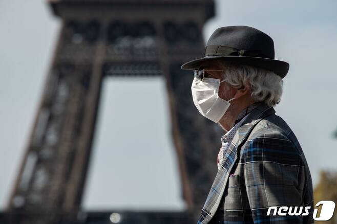 마스크를 착용한 노인이 프랑스 에펠탑을 앞을 지나쳐 걸어가고 있다. © AFP=뉴스1