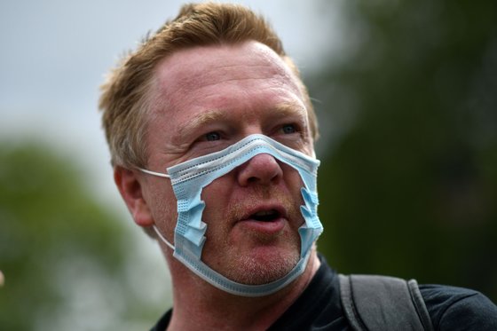 지난19일 영국 런던의 하이드파크에서 열린 마스크 착용 반대 시위에 참여한 한 남성이 마스크 착용 저항의 표현으로 코와 입 부분이 찢어진 마스크를 쓰고 있다. [AFP=연합뉴스]