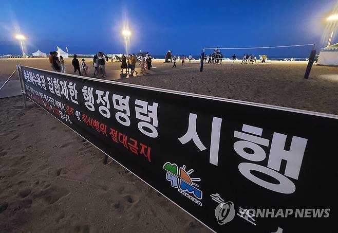 야간 취식행위 안됩니다 (속초=연합뉴스) 이종건 기자 = 강원 동해안 8개 주요 해수욕장에서 시행 예정인 야간 취식행위 단속을 앞두고 사전 계도 활동이 시작된 지난 18일 밤 속초해수욕장 입구에 집합제한 행정명령에 따른 단속 안내 현수막이 걸려있다. 2020.7.19 momo@yna.co.kr