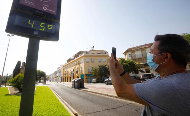 지난달 30일 스페인 코르도바에서 마스크를 쓴 한 시민이 섭씨 45도를 표시하고 있는 온도계를 촬영하고 있다. 스페인에서 13개 지역이 40도가 넘는 고온으로 폭염 경보를 발령했다. 코르도바=EPA 연합뉴스