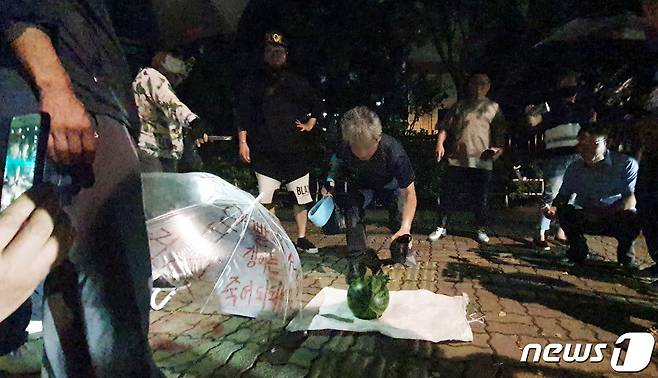 문재인 대통령을 향해 신발을 벗어 던진 뮤지컬 극단 '긍정의 힘' 정창옥 단장(57)이 19일 오후 법원의 영장이 기각되면서 서울 영등포경찰서 유치장을 나와 신발로 수박을 깨는 퍼포먼스를 하고 있다. 2020.7.19/뉴스1 © News1 황덕현 기자