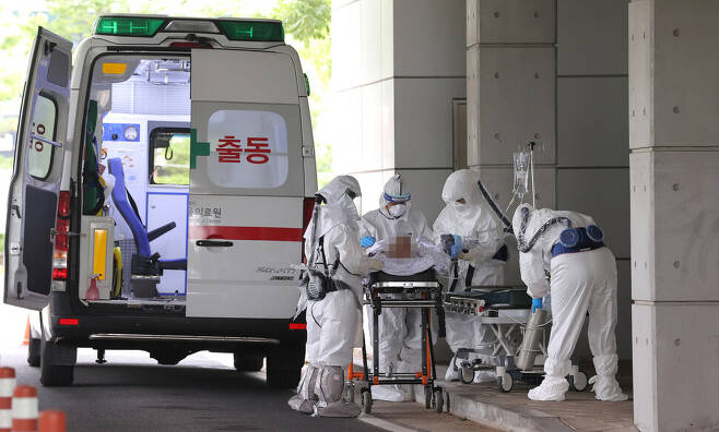 24일 오후 서울 중랑구 서울의료원에서 방호복을 입은 의료진이 코로나19 의심 환자를 이송하고 있다. 연합뉴스