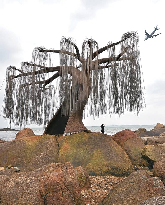 인천 영종도 북쪽의 작은 섬 모도의 배미꾸미조각공원 앞 해안에 설치된 조형물 ‘버들선생’. 굵은 철사를 붙여 버드나무를 형상화한 작품이다. 조형물 위로 인천공항을 이륙한 비행기가 지나가고 있다. 버드나무 형상 조형물의 높이는 3.2m. 바닷가에 서 있는 사람과의 거리 때문에 더 커 보인다.