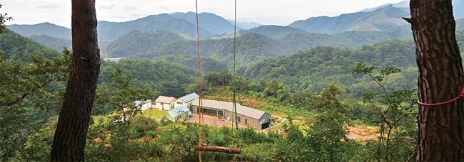 첩첩한 산의 구릉을 바라보는 야트막한 언덕 위에 앉아있는 강원 양양의 관광농원 ‘팜 일레븐’의 전경. 그네를 매어놓은 농원 뒤편 언덕 위에서 내려다본 모습이다. 팜 일레븐에서는 다소 밋밋하다 싶은 주변 경관이, 뜻밖에도 묵직한 미감으로 다가오는 경험을 할 수 있다.