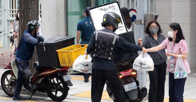 지난 1일 서울 세종대로 정부서울청사에서 공무원들이 오토바이로 배달된 점심 도시락을 받고 있다. 뉴스1