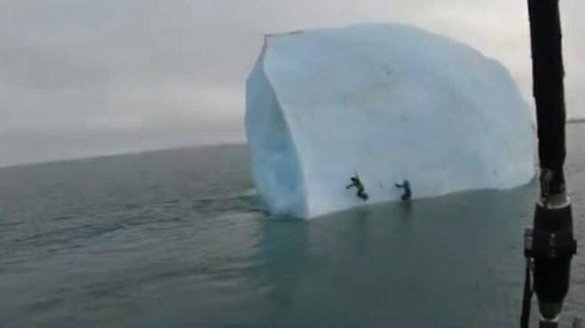 빙산이 기울어져 두 탐험가가 바다로 빠지기 직전이다.