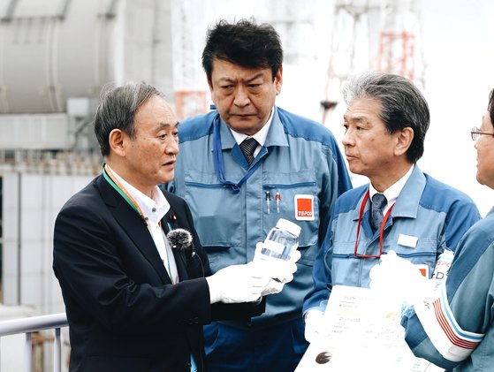 스가 요시히데(왼쪽) 일본 총리가 지난 26일 취임 후 처음으로 후쿠시마 제1원전을 방문해 도쿄전력 관계자의 설명을 듣고 있다. 스가 총리가 들고 있는 병 안에는 원전에서 발생한 오염수를 한 차례 정화한 물이 담겨있다. 스가 총리는 오염수 처리와 관련 "되도록 빨리 정부가 책임을 지고 처분 방법을 결정하겠다"고 말했다. [스가 총리 인스타그램]