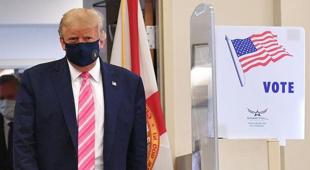 검은색 마스크를 착용한 도널드 트럼프 미국 대통령이 24일 플로리다주 팜비치의 사전투표소에서 대선 투표를 마친 뒤 걸어나오고 있다. 팜비치=AFP 연합뉴스