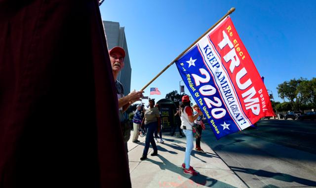도널드 트럼프 미국 대통령 지지자들이 지난 11일 캘리포니아주 로스앤젤레스의 한 거리에서 트럼프를 응원하는 의미의 깃발을 들고 서 있다. 로스앤젤레스=AFP 연합뉴스