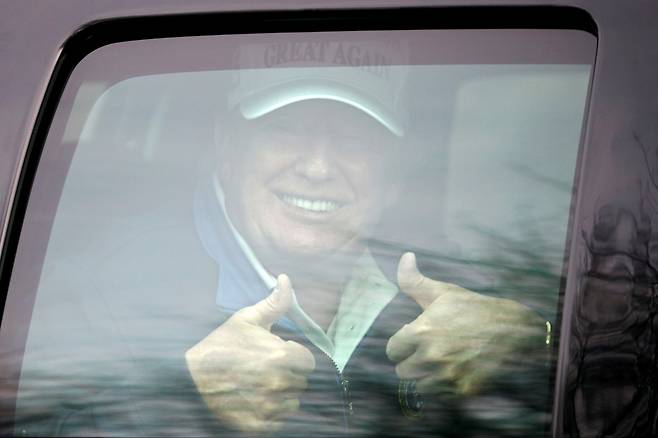 도널드 트럼프 미국 대통령이 22일(현지시간) 버지니아주에 위치한 트럼프 내셔널 골프 클럽으로 이동하는 차량 안에서 지지자를 향해 양손의 엄지 손가락을 들어 보이며 웃고 있다. [로이터]