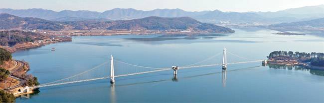 충남 논산 탑정호를 가로지르는 탑정호 출렁다리. 다리만 따지면 570m, 다리 양 끝 진입구간까지 합치면 600m로 국내 최장 출렁다리다. 주탑을 잇는 케이블에 촘촘히 매어놓은 강선에 LED 등을 달아 야간 시간대에 다리 전체를 스크린처럼 활용한다.