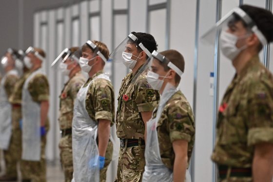 지난달 11일 영국 북서부 리버풀의 리버풀 전시센터에 설치된 코로나19 바이러스 신속 검사센터에서 검사를 담당하는 군인들이 도열해 있다. AFP=연합뉴스